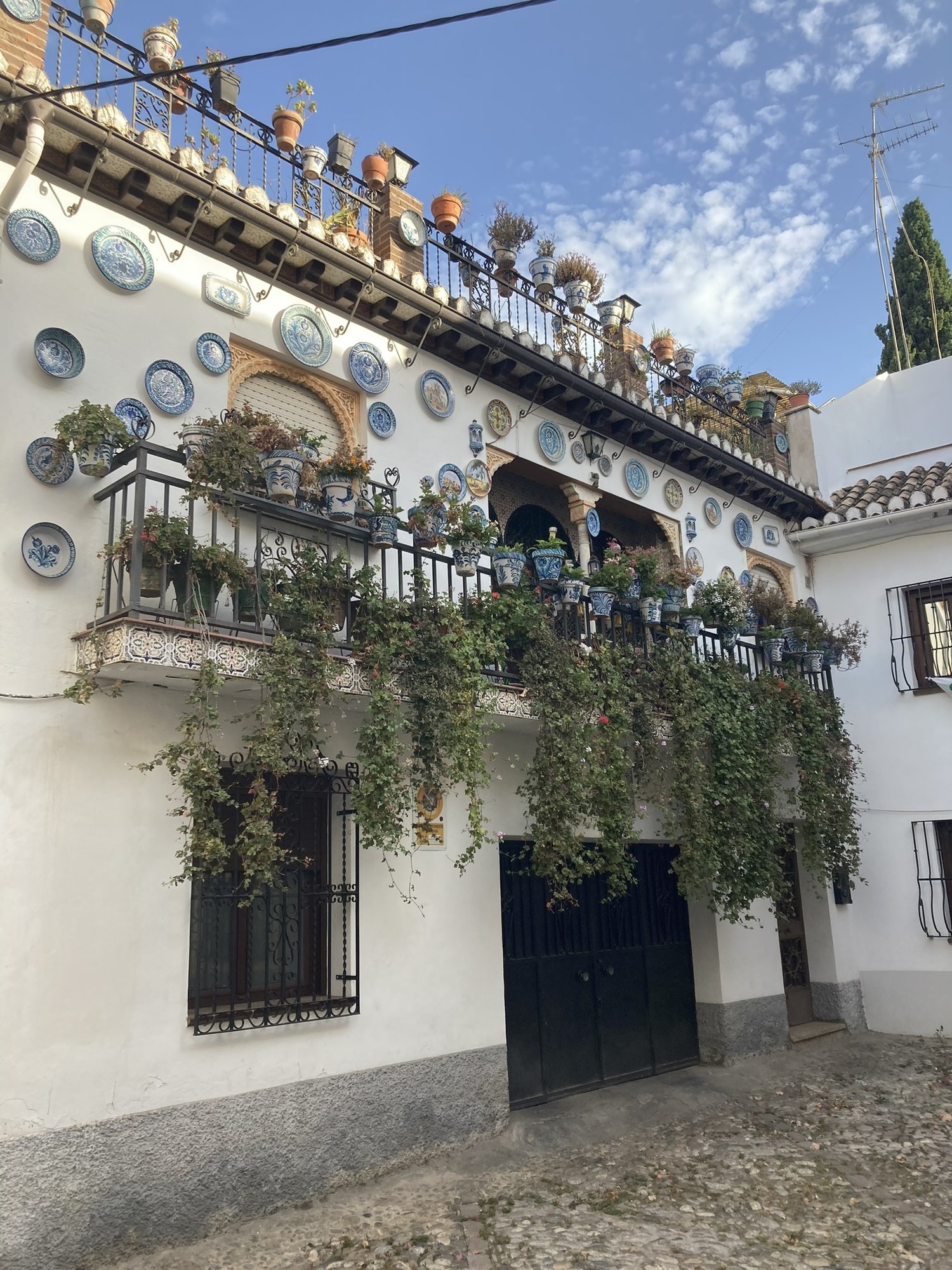 Maison blanchie à la chaux ornée d’assiettes en céramique et de fleurs dans l’Albaicín, à Grenade